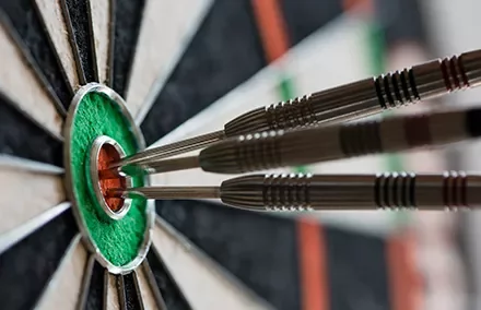 Three darts hitting the bullseye on a dartboard.