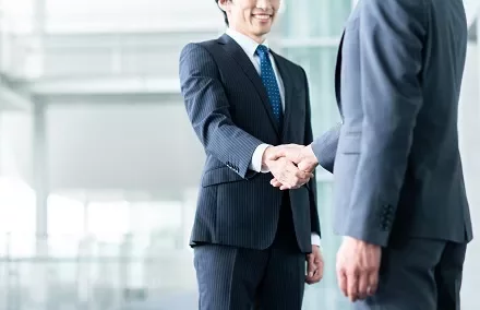 オフィスで握手を交わす二人のビジネスマン。