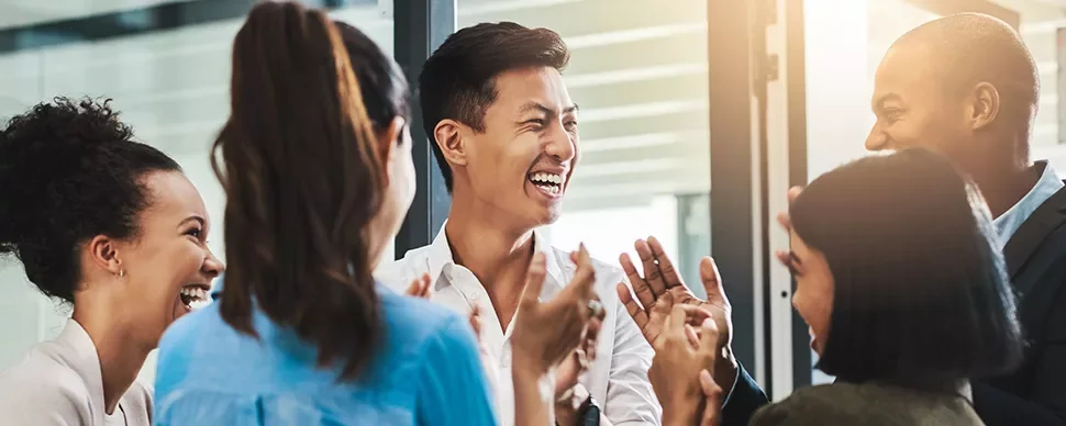 Group of people smiling and clapping in an office.