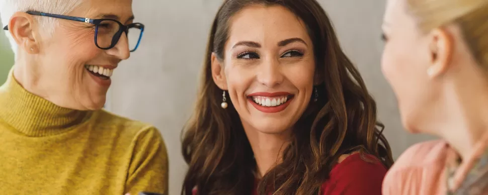 Three women smiling and chatting together.