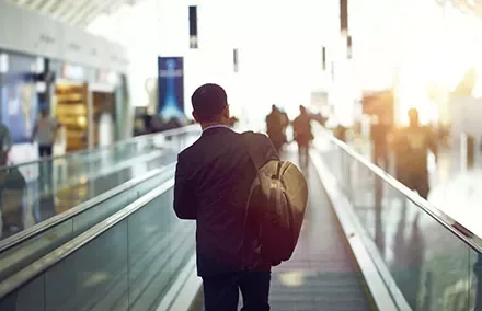 Person walking on airport moving walkway with backpack
