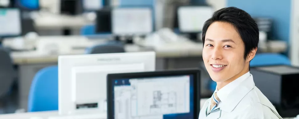 オフィスでコンピューターを使っている笑顔の人。
