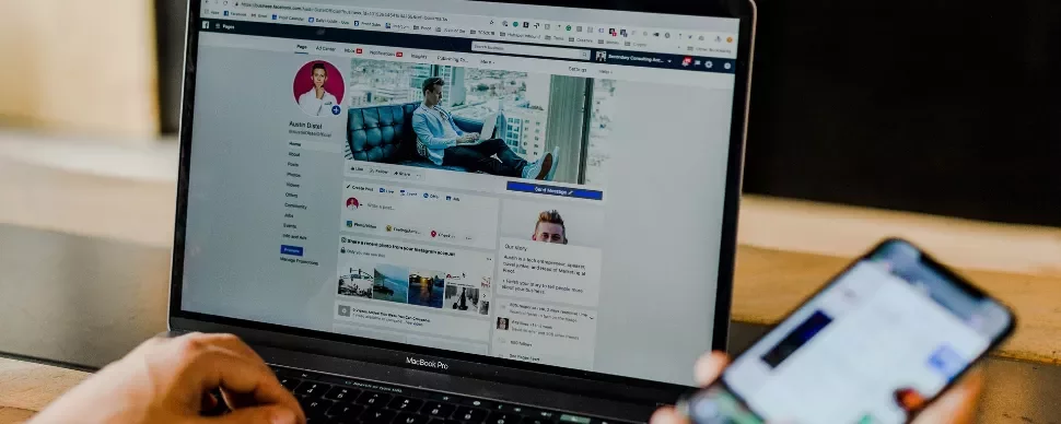 Person using laptop with social media profile and smartphone.