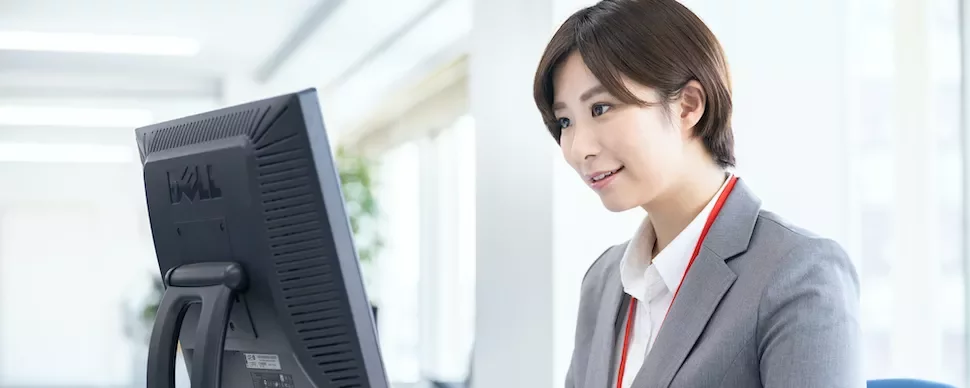 明るいオフィスでコンピューターを使うビジネスウーマン。