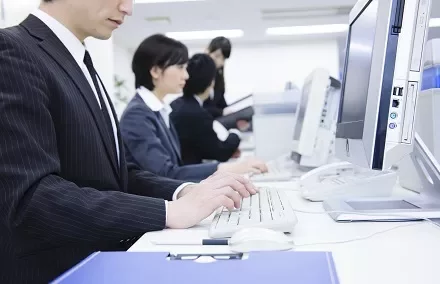 オフィスでコンピュータに向かう人々。