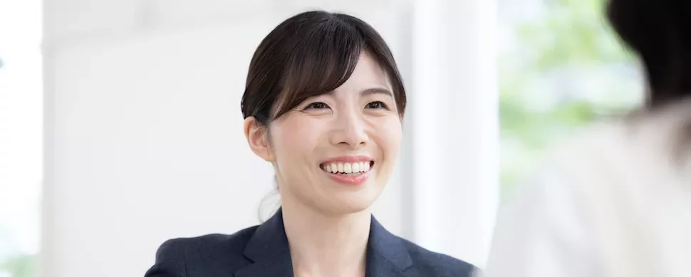 明るい部屋で会話中の笑顔の女性。