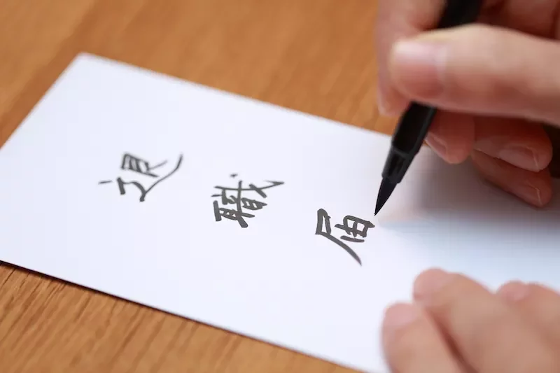 ペンで紙に日本語の文字を書く人。