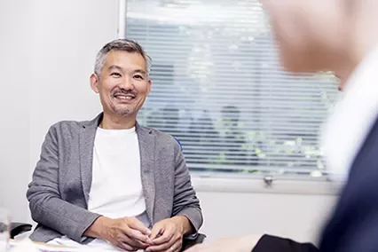 会議中に微笑む男性と向かい合う。