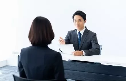 Man in suit conducting an interview at a desk.