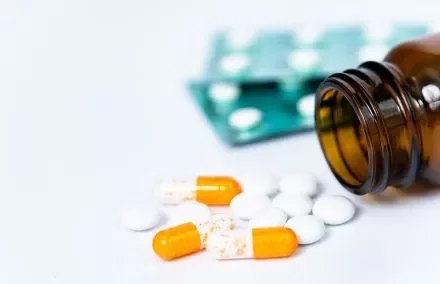 Brown bottle with orange and white pills and a blister pack.