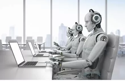 Robots seated at desks working on laptops in a modern office.