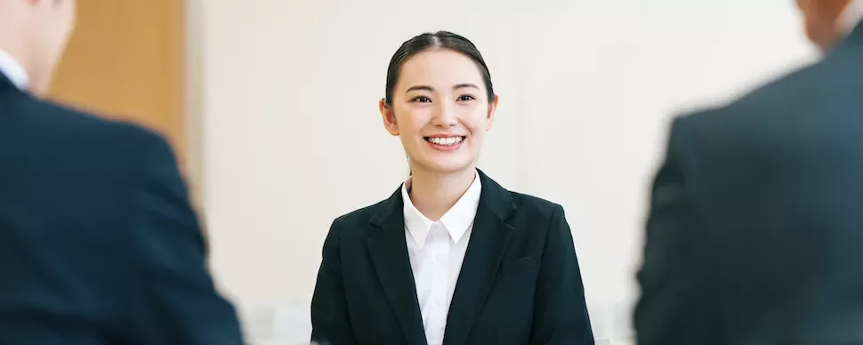 ビジネススーツを着た人物が会議で微笑んでいる。