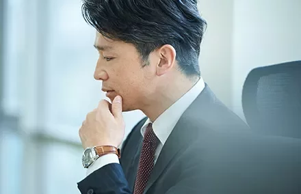 Business person in suit contemplating, side profile.