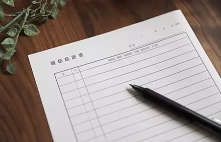 A pen rests on a blank Japanese form on a wooden desk.