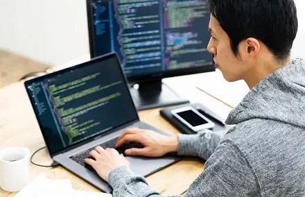 ラップトップでコードを書く人。
