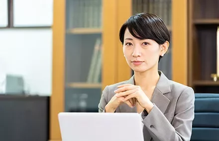 Businesswoman sitting at a desk with a laptop, looking professional.